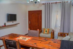 a living room with a wooden table and a television at Upland Estates Serviced Apartments in Lusaka