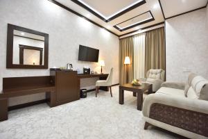 um quarto de hotel com uma secretária e uma sala de estar em Qushbegi Plaza Hotel em Tashkent