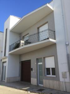 Cette maison blanche dispose d'un balcon et d'un garage. dans l'établissement Kaloneiro Guest House, à Corigliano dʼOtranto