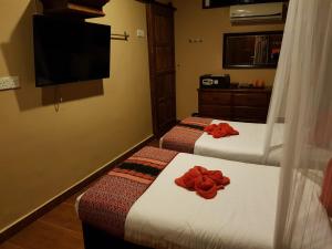 two beds in a hotel room with red flowers on them at Ombak Dive Resort Perhentian Island in Perhentian Islands