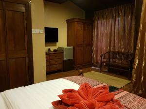 a bedroom with a bed and a dresser and a television at Ombak Dive Resort Perhentian Island in Perhentian Islands