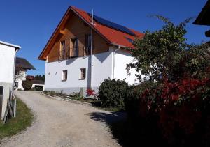 una casa blanca con techo rojo y un camino de tierra en Landhof Sedlmair en Gilching