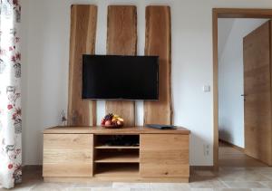 uma televisão num centro de entretenimento de madeira numa sala em Landhof Sedlmair em Gilching