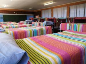 eine Gruppe von Betten in einem Zimmer mit einem Klassenzimmer in der Unterkunft Dirkie Uys Backpackers in Durban