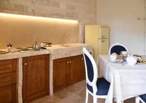 a kitchen with a sink and a table and a refrigerator at Trulli e Puglia Luxury Suite in Alberobello