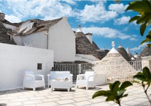 a patio with white chairs and a building at Trulli e Puglia Luxury Suite in Alberobello