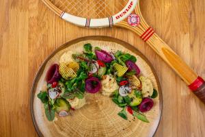 a plate of vegetables on a table with a tennis racket at Hotel Rodan in Kórnik