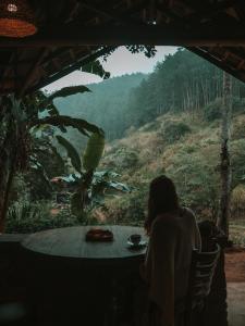 a woman sitting at a table looking out at the forest at Arawe Retreat in Ella