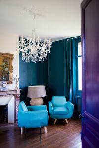 a living room with blue chairs and a chandelier at Le Jardin, chambres d'hôtes en Baie de Somme in Cahon