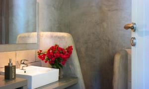 a bathroom with a sink and a vase of red flowers at Anima Apartments in Chora Folegandros