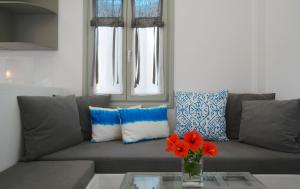 a living room with a couch and a vase with red flowers at Anima Apartments in Chora Folegandros
