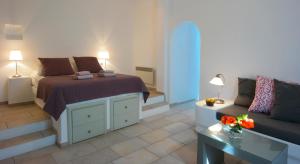 a bedroom with a bed and a couch and a table at Anima Apartments in Chora Folegandros