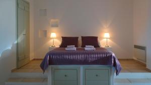 a bedroom with a bed with purple sheets and two lamps at Anima Apartments in Chora Folegandros