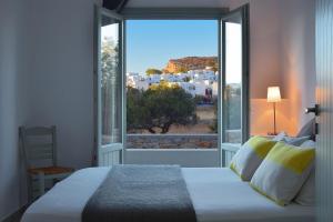 a bedroom with a bed and a large window at Anima Apartments in Chora Folegandros