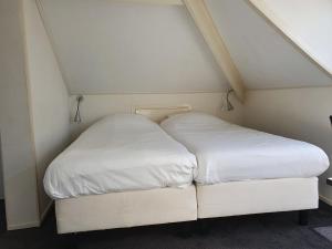 two beds in a small room with white sheets at De Wentehoeve in Oostkapelle