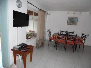une salle à manger avec une table, des chaises et une télévision dans l'établissement Villa Raybaud Résidence Les Cygnes, à Pereybere