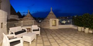 a patio with white chairs and a fence at night at Trulli e Puglia Luxury Suite in Alberobello