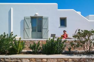 una mujer sentada en la cornisa de una casa blanca en Anima Apartments, en Chora Folegandros