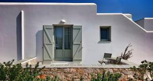 a white house with a green door and a table at Anima Apartments in Chora Folegandros