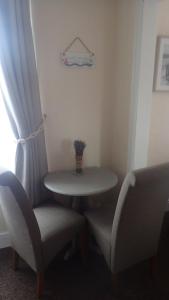a small table and two chairs with a table and a window at The Victoria guest house in Mablethorpe