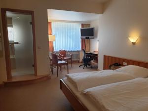 ein Hotelzimmer mit einem Bett, einem Schreibtisch und Stühlen in der Unterkunft Hotel Hessischer Hof in Melsungen