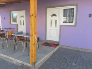 a house with a purple wall and a table and chairs at SubotićSmještaj in Kulaši