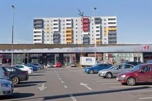 奥拉迪亚Panoramic Studio Oradea的建筑物前停放汽车的停车场