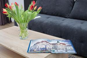 Eine Vase voller Blumen und ein Buch auf dem Tisch in der Unterkunft Panoramic Studio Oradea in Oradea