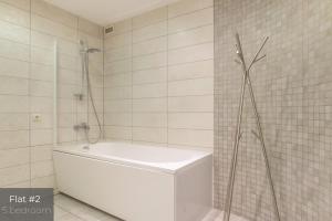 La salle de bains est pourvue d'une baignoire blanche et d'une douche. dans l'établissement Dandelion Apartments Lāčplēša, à Riga 68 autres photos