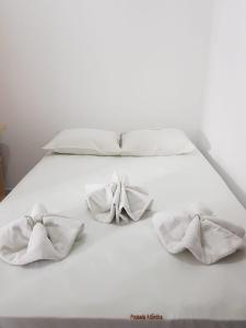 ein weißes Bett mit drei Handtüchern drauf in der Unterkunft Kitnets Izidro - TAMBAÚ in João Pessoa