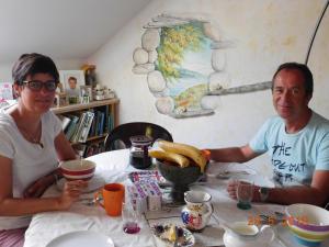 Ein Mann und eine Frau sitzen an einem Tisch in der Unterkunft Chez Nous. B & B in Bassy