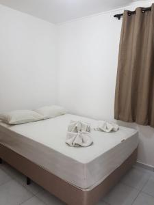 ein weißes Bett mit weißen Schuhen darüber in der Unterkunft Kitnets Izidro - TAMBAÚ in João Pessoa