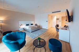uma sala de estar com uma cama e uma cadeira azul em Antunović Hotel East em Sesvete