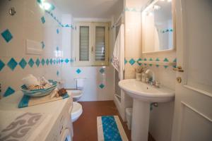 a white bathroom with a sink and a toilet at Casa Delta delle Acque Vista spettacolare e Giardino in Cala Gonone