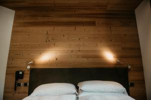 two beds in a room with a wooden wall at Alpen Hotel Chalet in Valdidentro