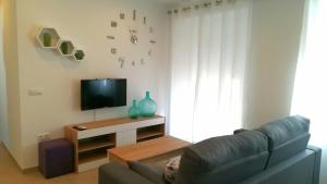 een woonkamer met een bank en een televisie bij Apartamento Jazmín 49 Centro - Adults Recommended in Nerja