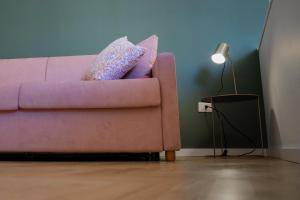a pink couch in a living room with a lamp at Teatro Suites Rooms in Catania