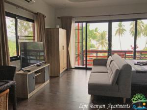 丽贝岛Lipe Banyan Apartments的客厅配有床、沙发和电视。