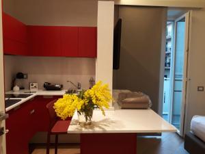 a kitchen with red cabinets and a vase of yellow flowers at Casa Due Maggio in Cava deʼ Tirreni