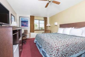 a hotel room with a bed and a flat screen tv at Days Inn by Wyndham Pueblo in Pueblo