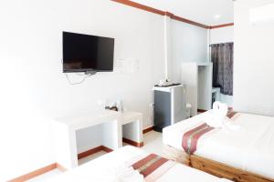 a room with two beds and a tv on the wall at Jarawee Resort in Chumphon