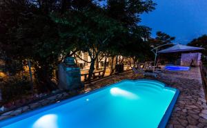 een blauw zwembad in een tuin 's nachts bij Apartmani Mabele in Pag