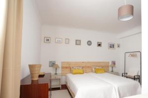 a white bedroom with a large white bed and yellow pillows at oporto airport house in Padrão