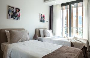 two beds in a bedroom with a window at Deluxe Apt w/ Rooftop Pool in The Heart of Kyrenia in Kyrenia