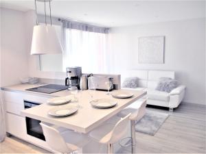 een witte keuken met een tafel en stoelen in een kamer bij Le White Cosy à 5 minutes du Lac avec parking privatif gratuit in Annecy