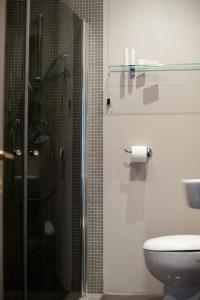 La salle de bains est pourvue de toilettes et d'une douche en verre. dans l'établissement Hotel Italia, à Noli