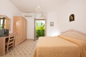 sypialnia z łóżkiem, biurkiem i telewizorem w obiekcie Hotel Candia w mieście Ischia