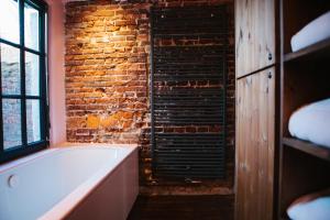 a bathroom with a brick wall and a bath tub at Friday Gent in Ghent