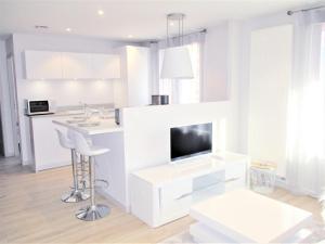 een witte woonkamer met een tafel en een televisie bij Le White Cosy à 5 minutes du Lac avec parking privatif gratuit in Annecy