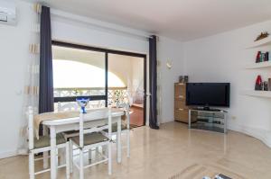 una sala da pranzo bianca con tavolo e TV di Apartment Aveiros Beach- D´Alma Amado a Vale de Pedras